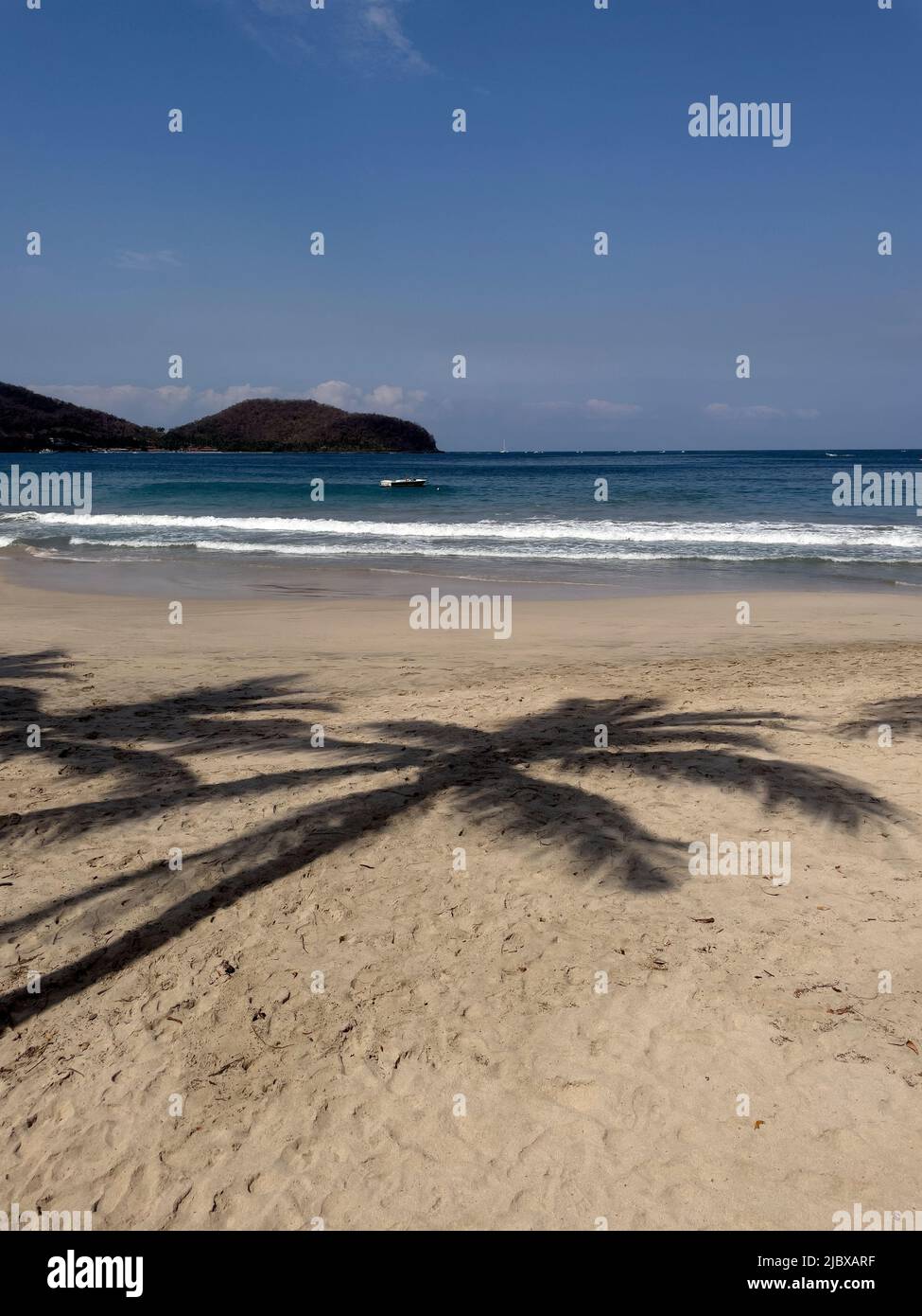 Sombra de palmera en la playa de arena de La Playa Ropa en Zihuatanejo, México Foto de stock