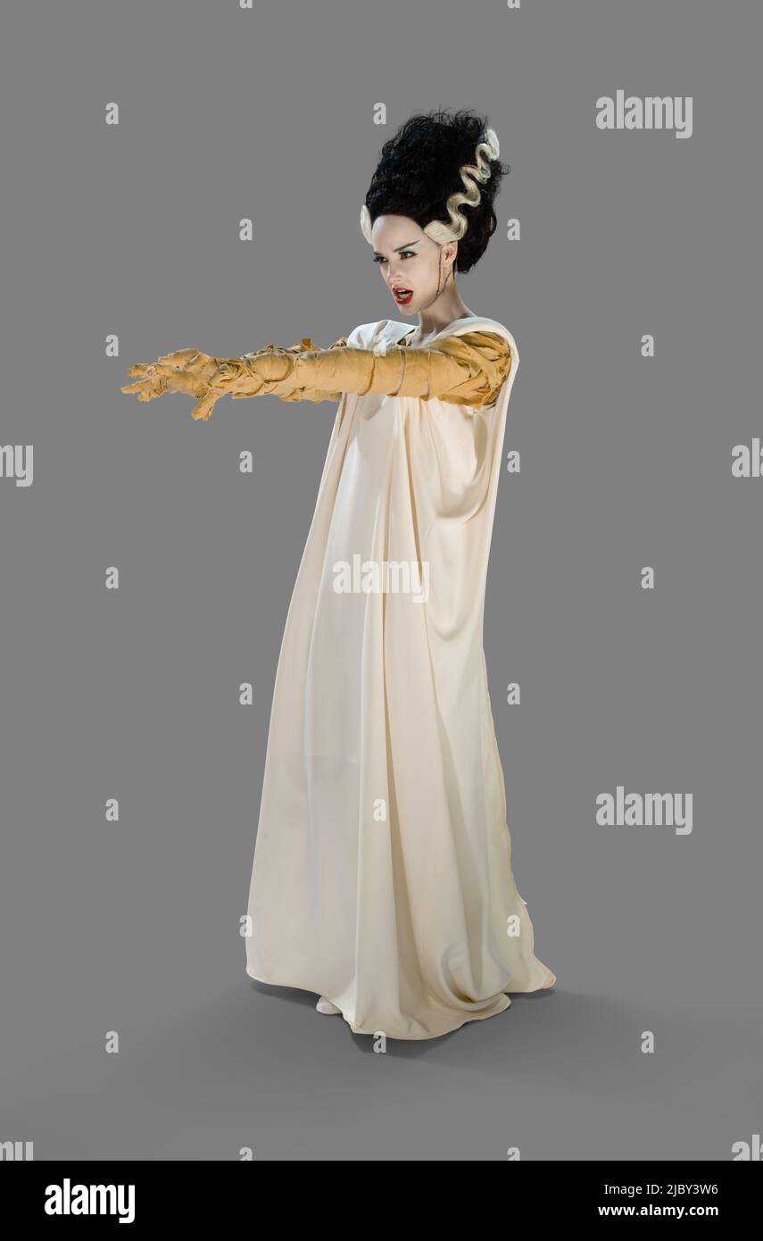 Mujer vestida como la Novia de Frankenstein disfraz de Halloween,  sosteniendo sus brazos mirando fuera de la cámara, contra un fondo gris  Fotografía de stock - Alamy