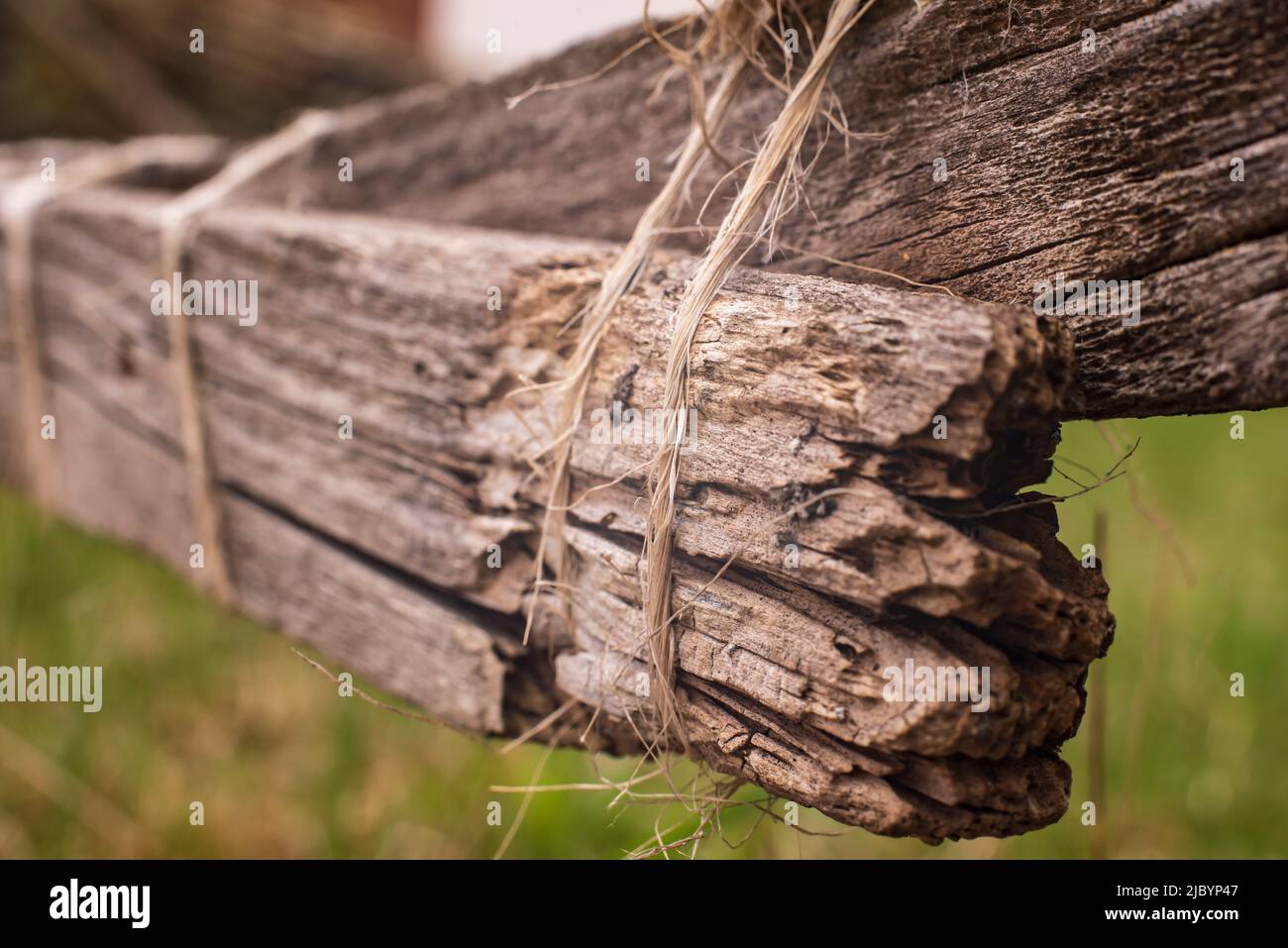 los tablones rotos de una valla rústica de madera reparados provisionalmente con una cuerda Foto de stock