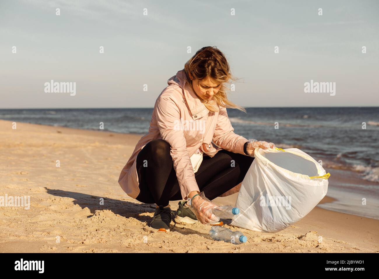 Mujer activista y asistente limpiando la playa de la basura submarina, el mar, el océano con residuos plásticos. Contaminación ecológica Foto de stock