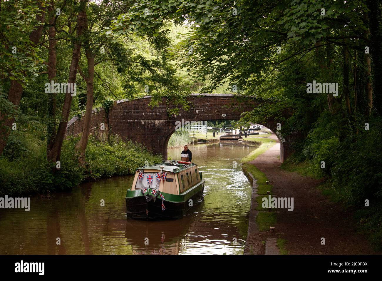 Un barco por el canal representado a lo largo del canal de Coventry en Atherstone, North Warwickshire. Foto de stock
