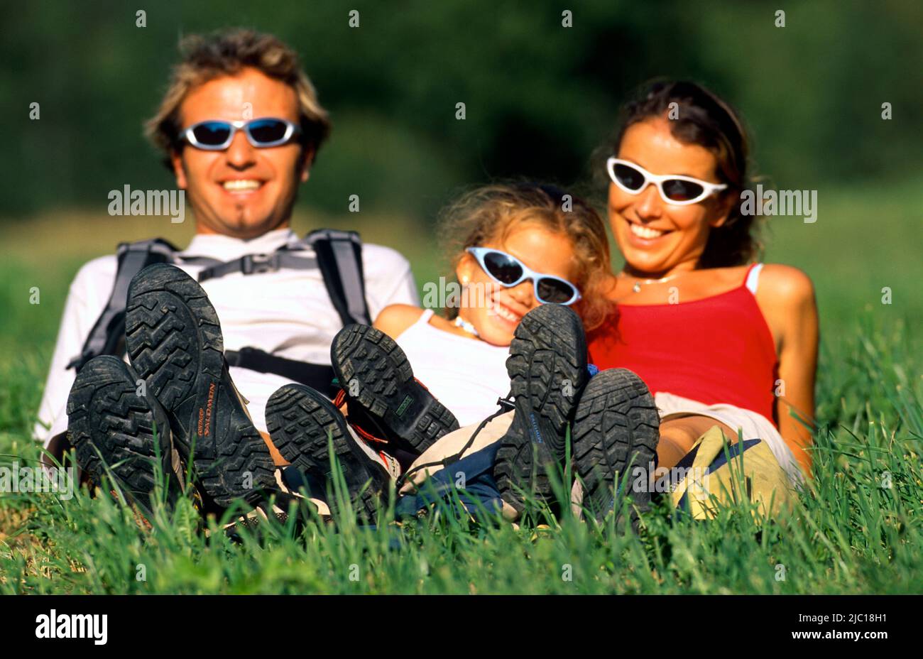 padre, madre e hija acostada en prado, haciendo freno durante una excursión de senderismo, , , Foto de stock