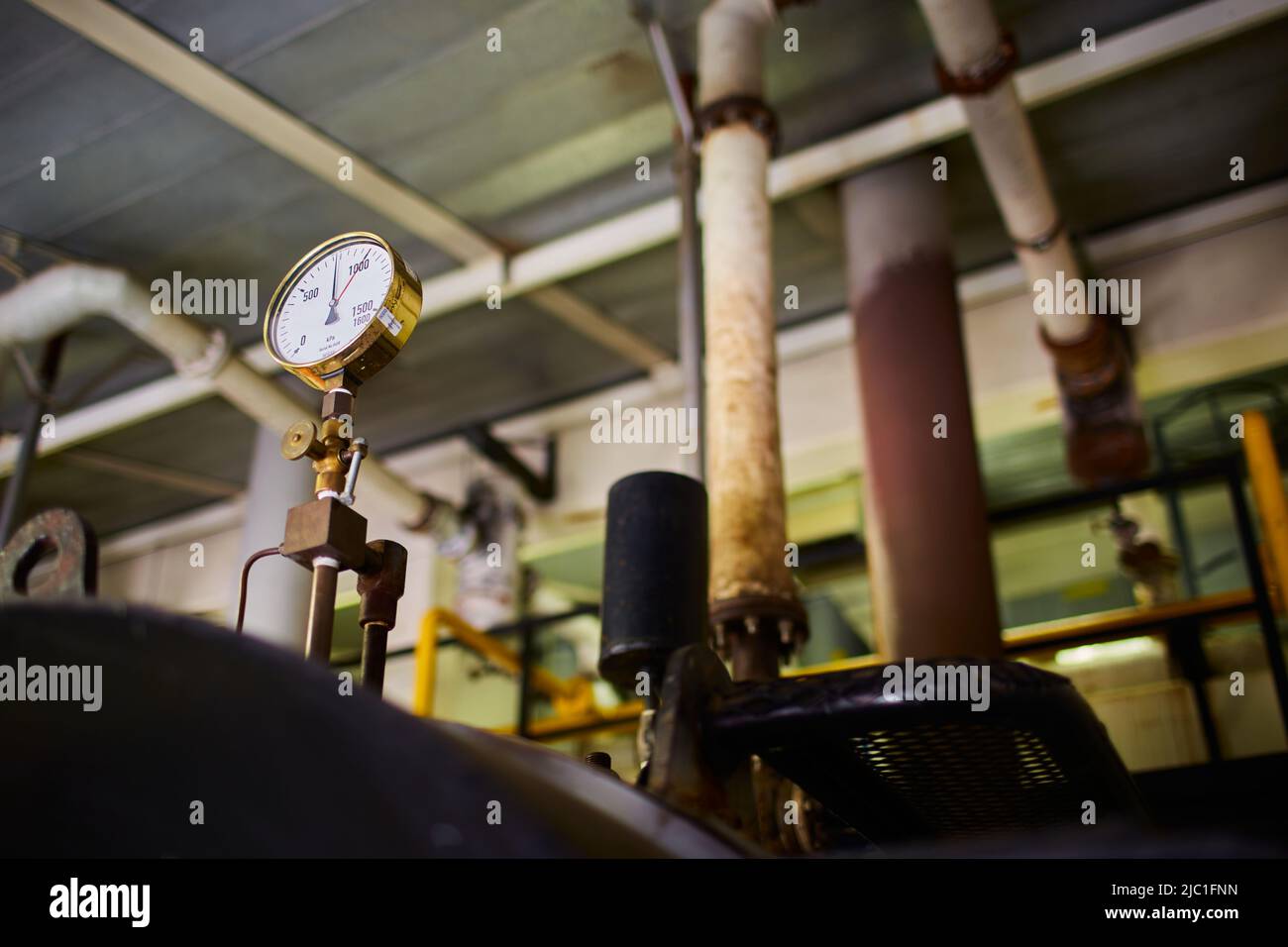Dial de la válvula de presión en una sala de calderas de vapor. Tanques de vapor con tuberías y rezagados. Foto de stock
