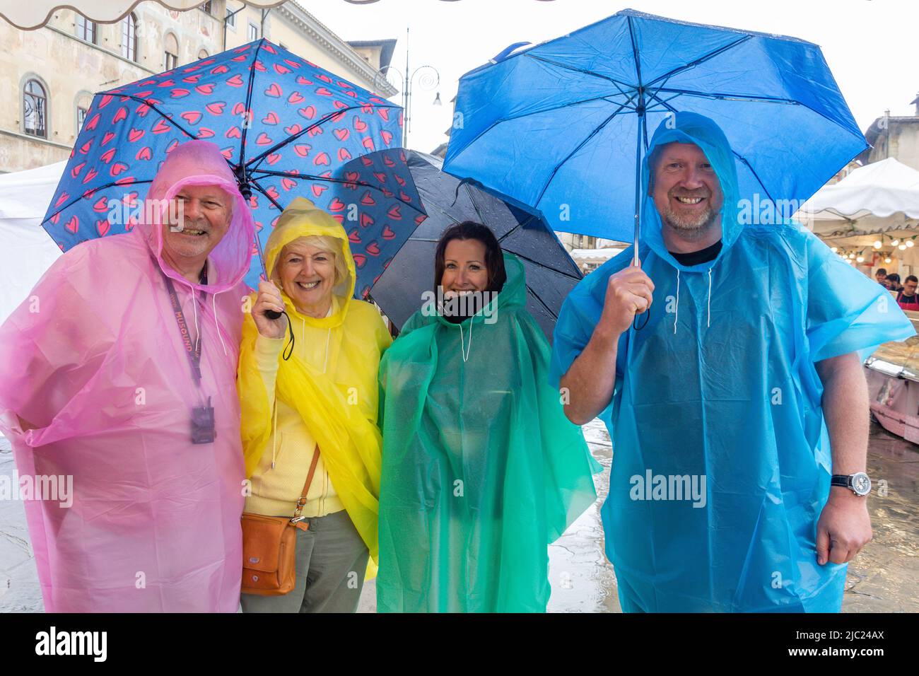 Grupo familiar bajo la lluvia con coloridos impermeables y sombrillas, Piazza di Santa Croce, Florencia (Florencia), Toscana, Italia Foto de stock