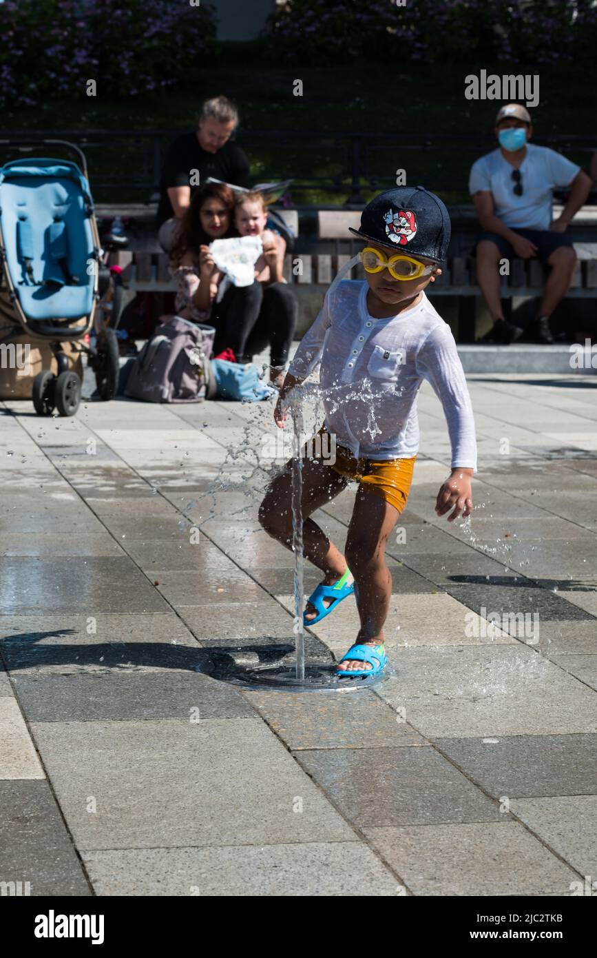 Ixelles, Región Capital de Bruselas -Bélgica - 06 22 2020 Pequeño niño negro jugando en una fuente de agua durante una ola de calor Foto de stock