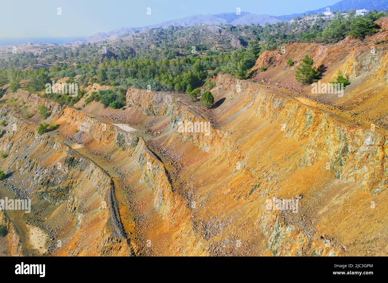 Reforestación de la antigua mina a cielo abierto. Pinos que crecen en la pared escalonada de mina de sulfuros abandonada en Limni, Chipre Foto de stock