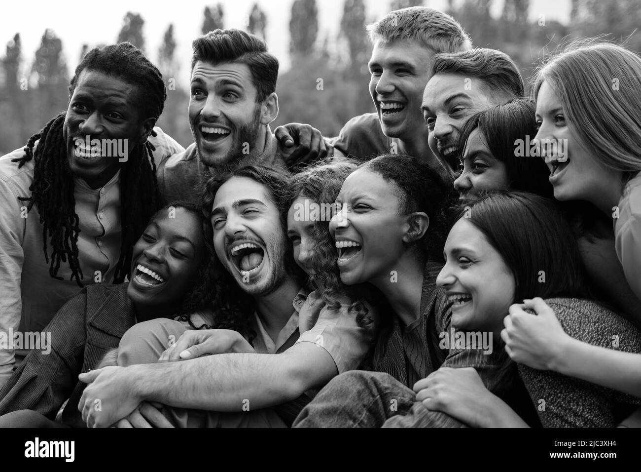 Multiétnico feliz grupo de personas que se divierten al aire libre - Enfoque en el centro de la niña africana - Edición en blanco y negro Foto de stock