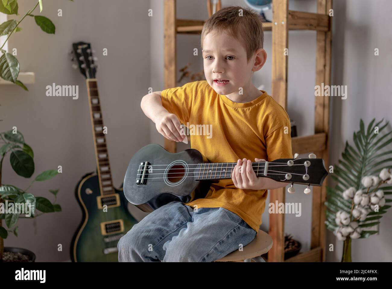 Lindo niño divertido está tocando la guitarra de ukulele en la sala de  música. Aprendizaje alegre para tocar instrumentos musicales Fotografía de  stock - Alamy