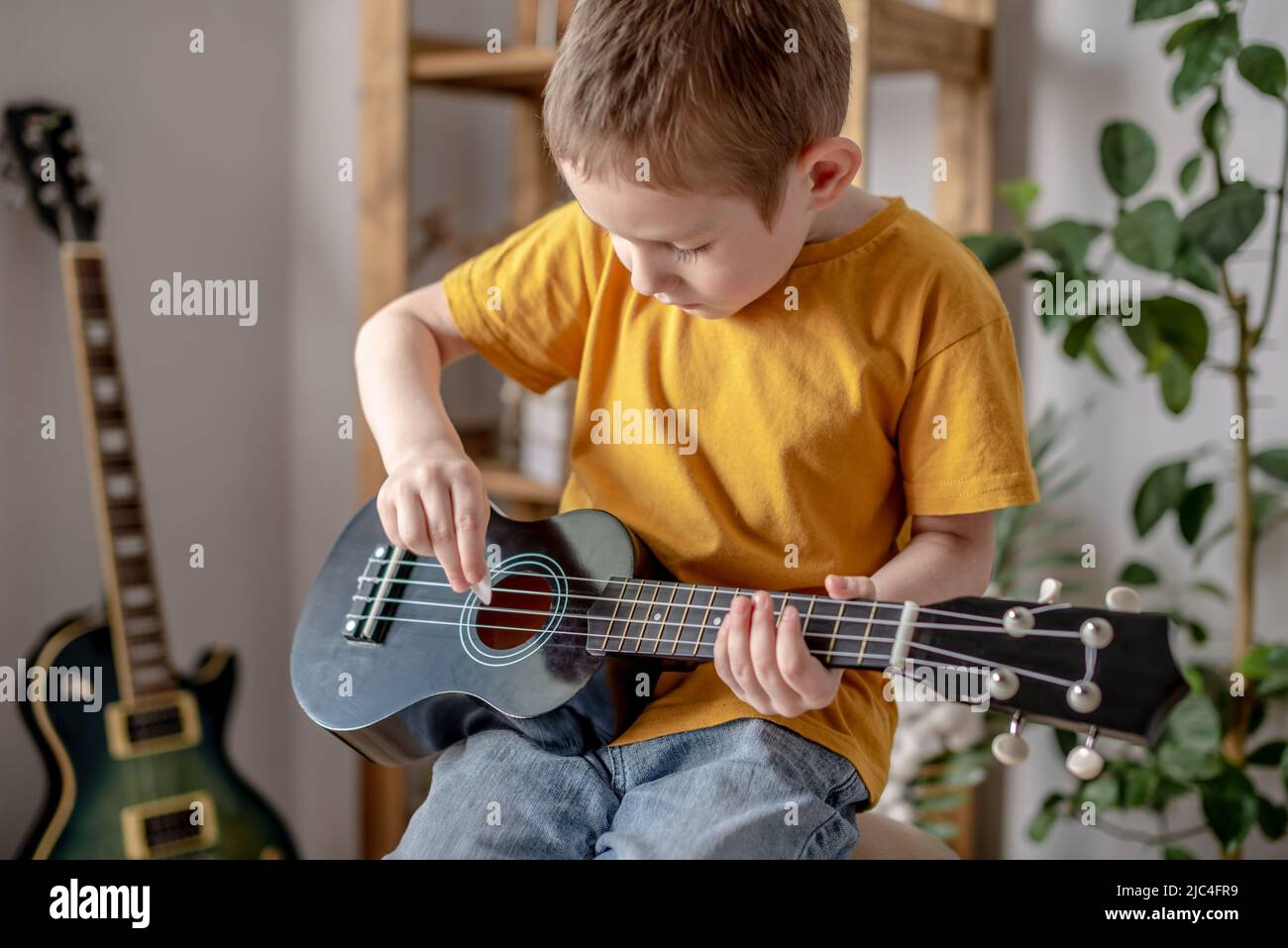 Lindo niño divertido está tocando la guitarra de ukulele en la sala de  música. Aprendizaje alegre para tocar instrumentos musicales Fotografía de  stock - Alamy