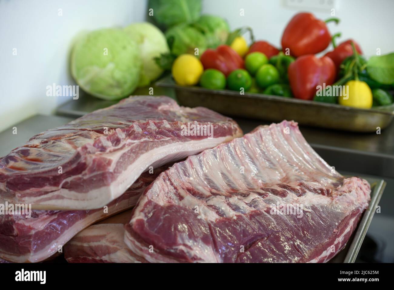 Costillas de cerdo y una bandeja de verduras y fuit de colores vivos. Foto de stock