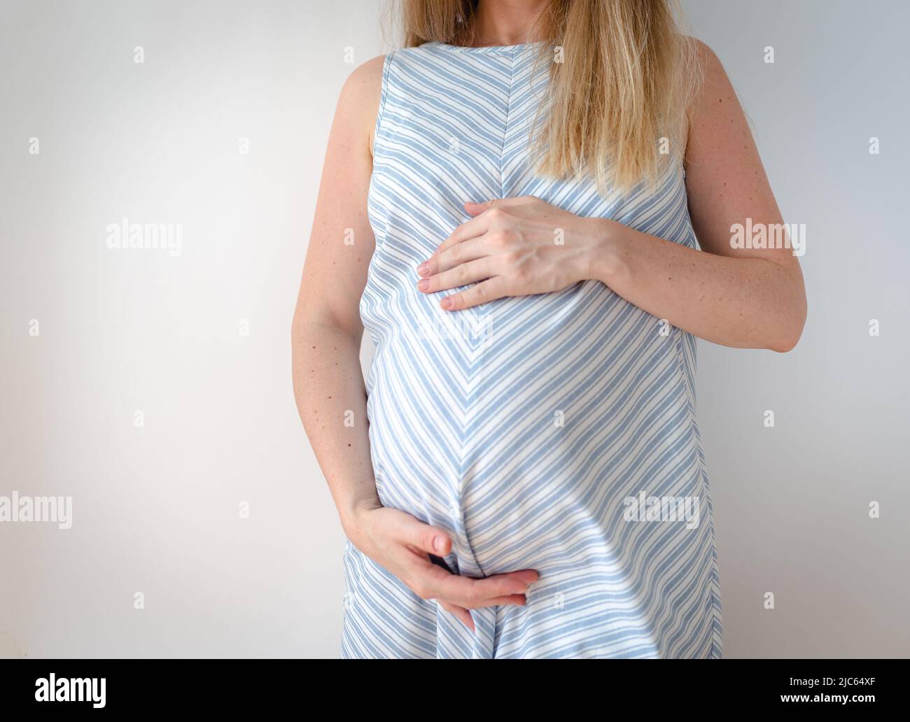 mujer embarazada de pie sosteniendo sus manos sobre su estómago Foto de stock