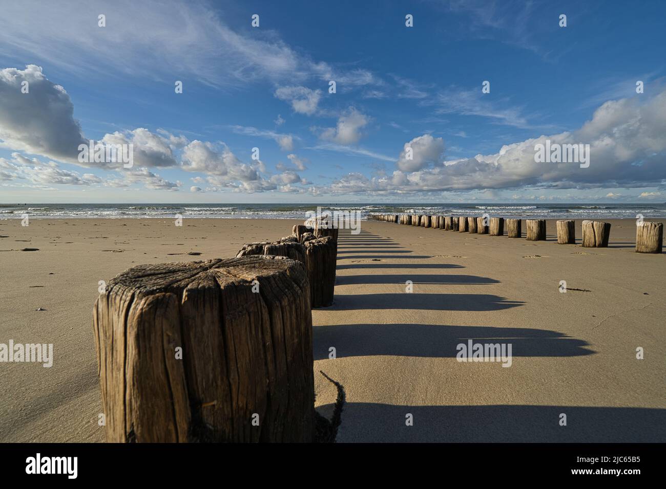 Antiguas palisades de madera en la playa con el mar y las nubes en el fondo Foto de stock