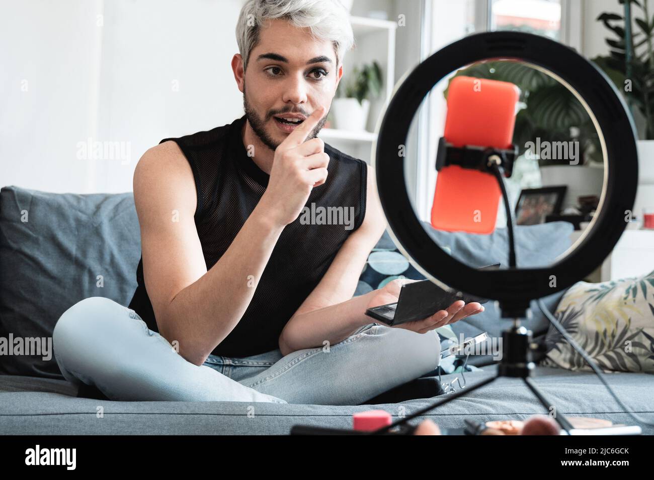 Transgender influencer streaming en línea maquillaje vídeo tutorial en las redes sociales en el hogar - LGBT, gay, género fluido concepto Foto de stock