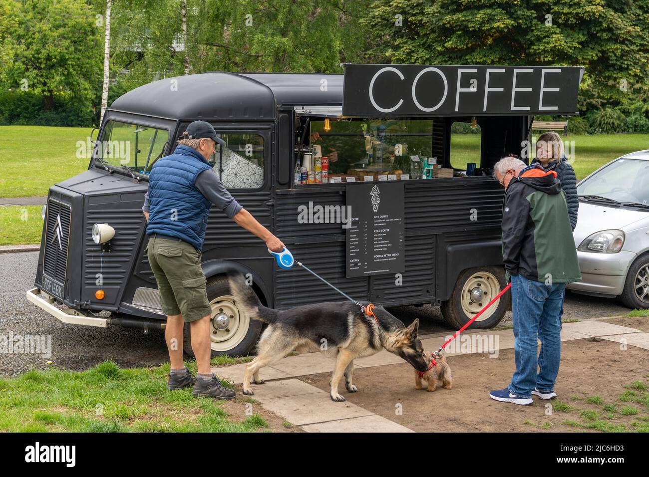 El perro grande se encuentra con el perro pequeño en una camioneta de café en Gosforth, Newcastle upon Tyne, Reino Unido. Foto de stock
