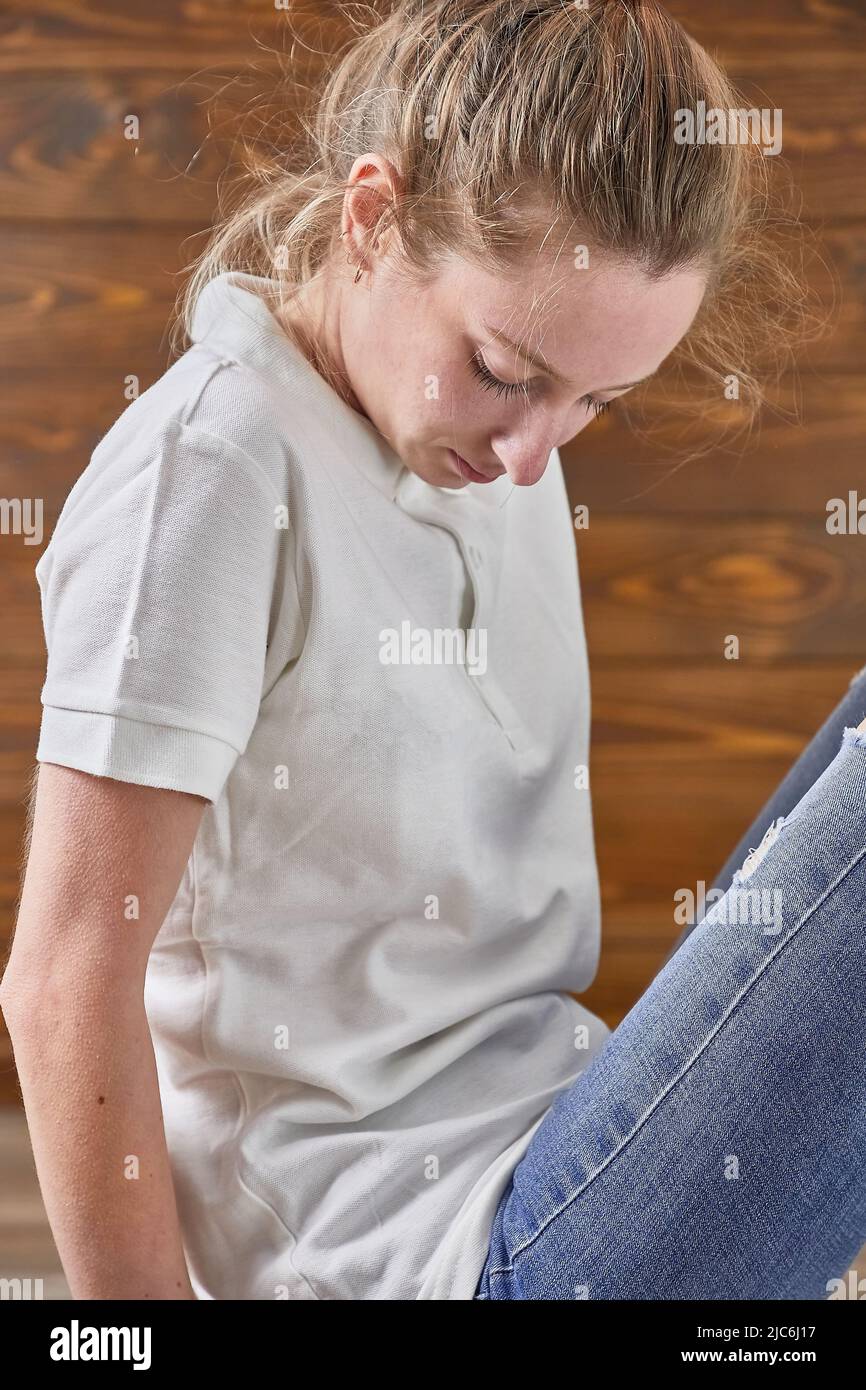 Chica en camiseta sentada en el suelo Foto de stock