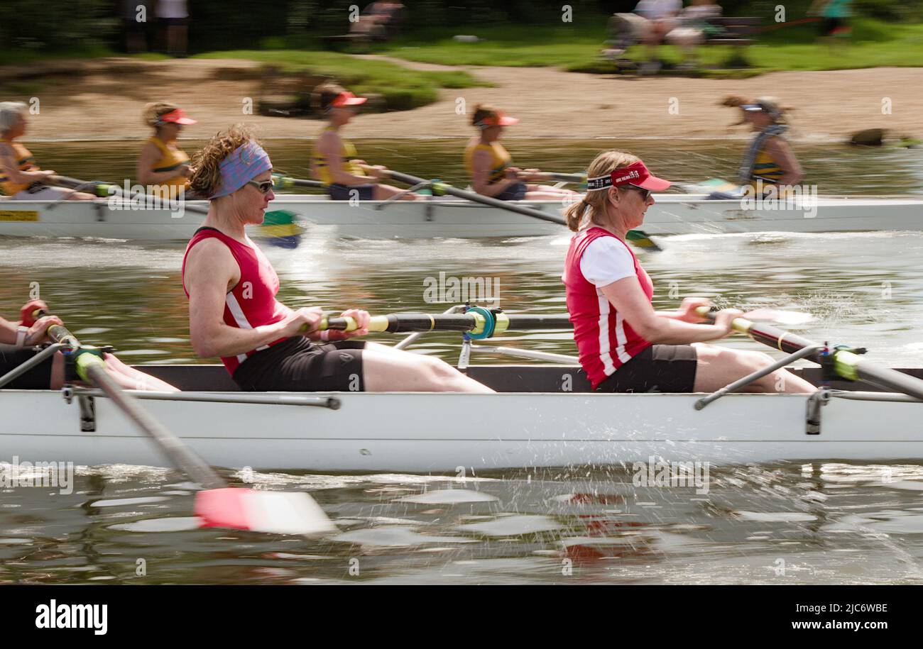 Movimiento Blur de mujeres barrer cortacéspedes que participan en una carrera en Christchurch Rowing Regatta en el río Stour Chrsitchurch Reino Unido Foto de stock