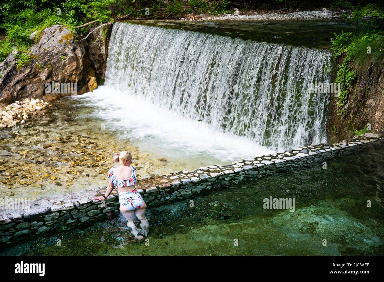 Mujer rubia en traje de baño bañándose en las aguas termales de Loutra Pozar Foto de stock
