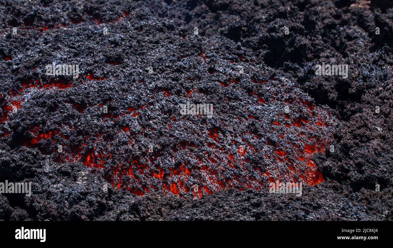 Lava incandescente fluye en el volcán Etna en Sicilia en el Valle del Bove con humo y lava canal de flujo Foto de stock