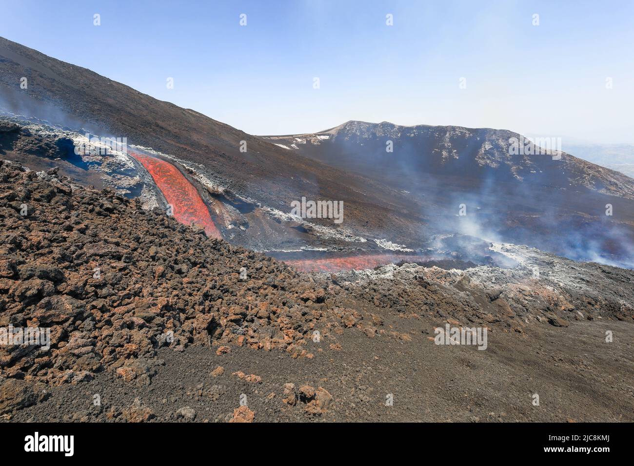 Etna-Colata di lava incandescente che scorre sul vulcano di Sicilia nella Valle del Bove con fumo e canale di scorrimento lavico Foto de stock