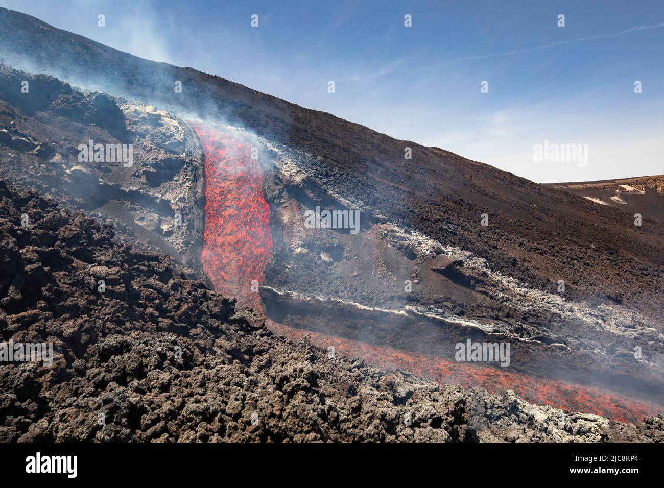Flujo de lava etna: La caída de lava sobre el volcán de Sicilia en Valle del Bove con humo y el canal de flujo de lava Foto de stock