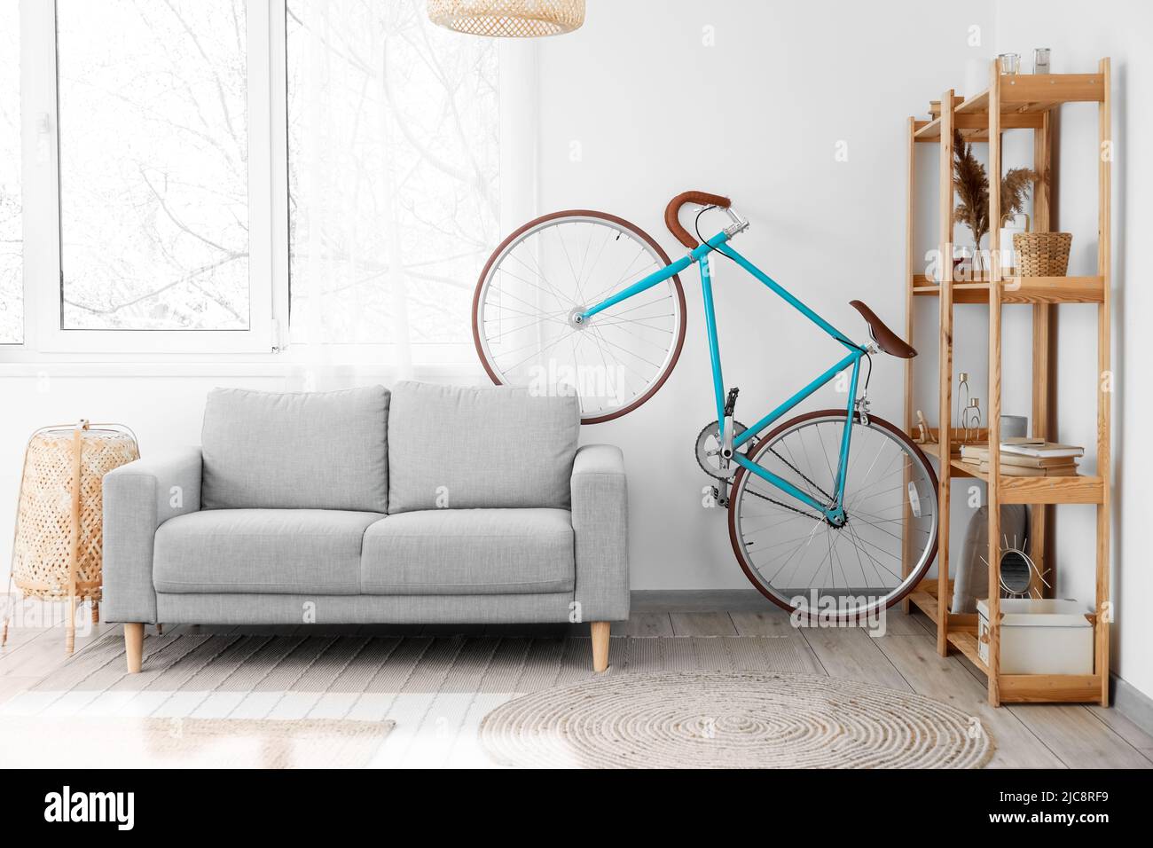 Interior de salón luminoso con bicicleta, sofá gris y estantería de madera  Fotografía de stock - Alamy