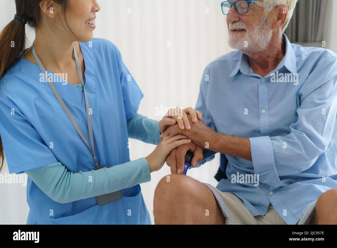 Enfermera asiática sentada en una cama de hospital junto a un hombre mayor ayudando a las manos, cuidando. Atención al paciente de edad avanzada y estilo de vida de salud, concepto médico. Foto de stock