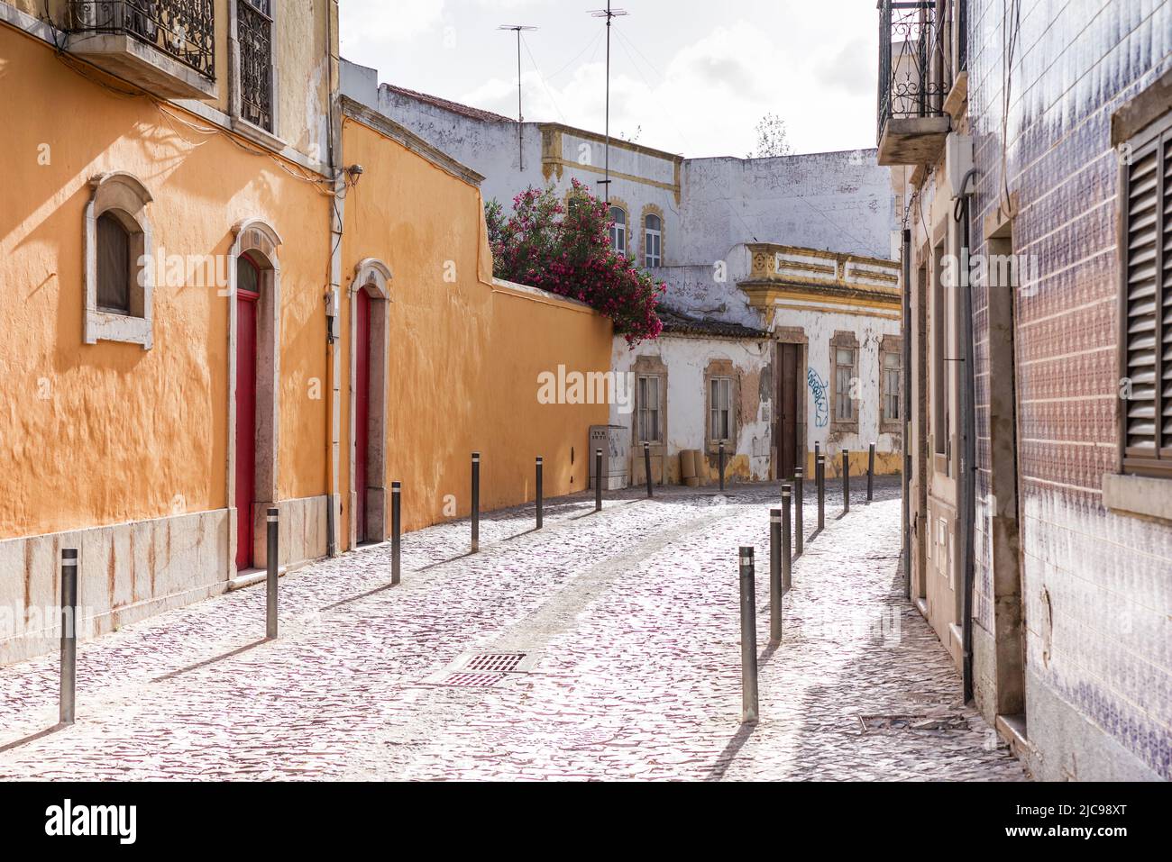 Pintoresca calle lateral disfrutando del sol de la tarde - Tavira, Portugal Foto de stock