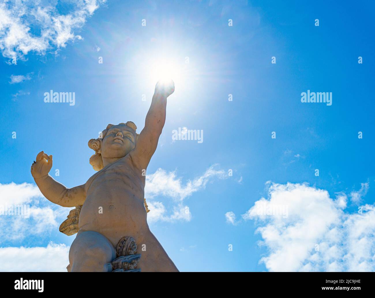Estatua de niño ángel con cielo nublado en el fondo Foto de stock