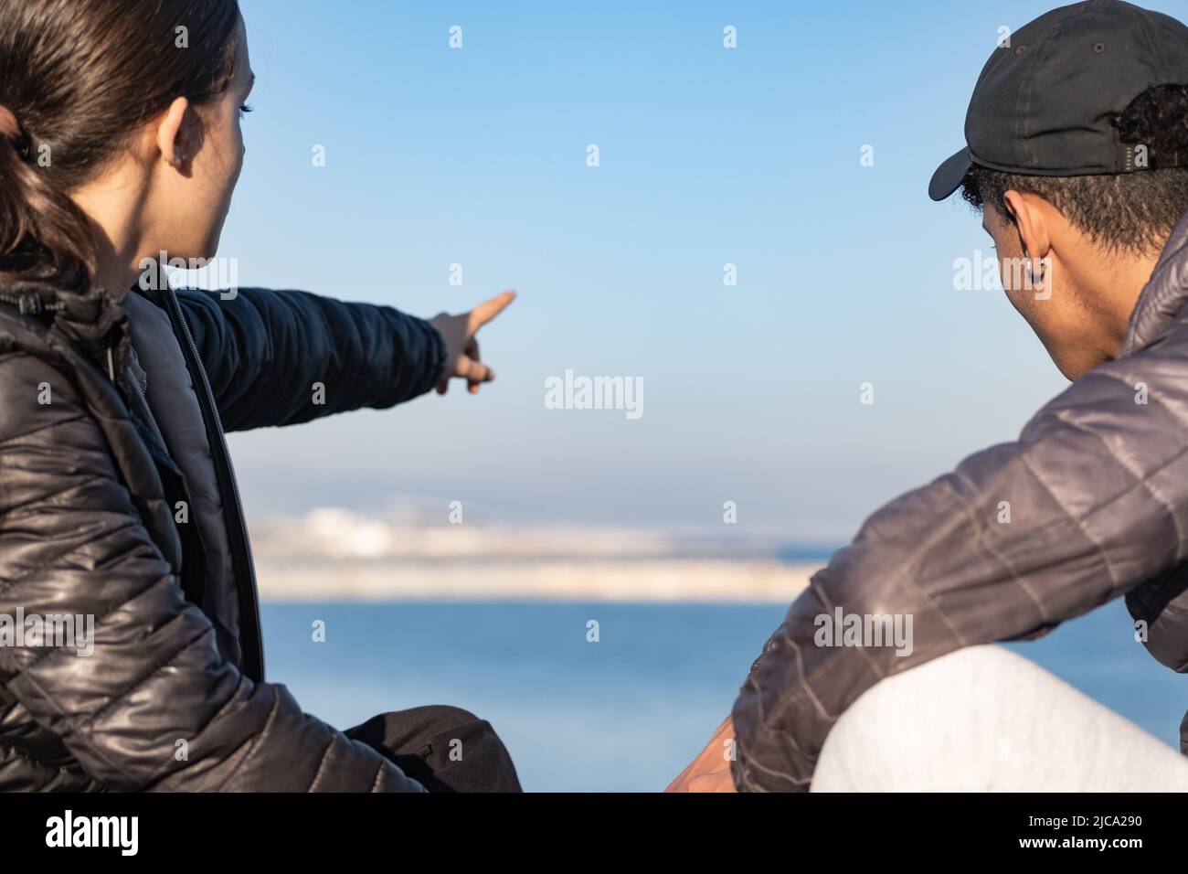Una pareja disfruta y mira al mar. Vista trasera. Enfoque en primer plano. Foto de stock