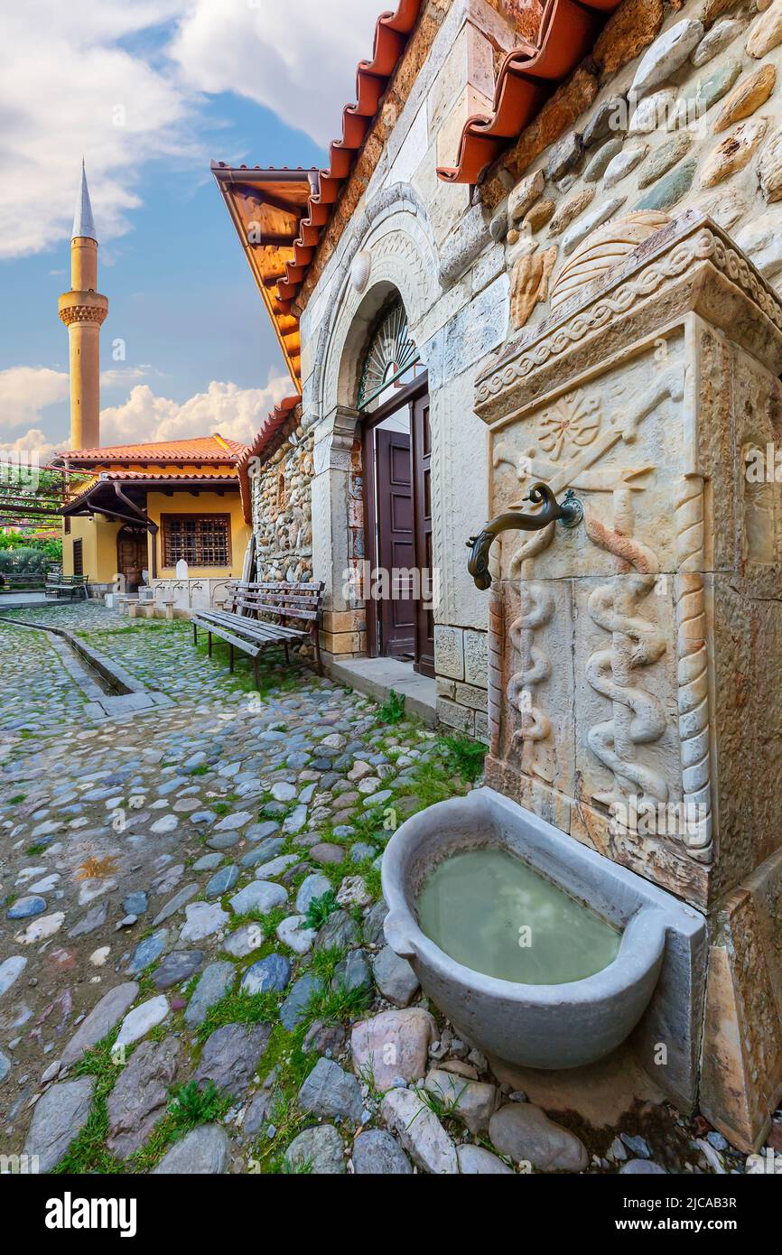Antigua fuente del templo sufi con el minarete de la mezquita Tekke de Halveti al fondo, Prizren, Kosovo Foto de stock