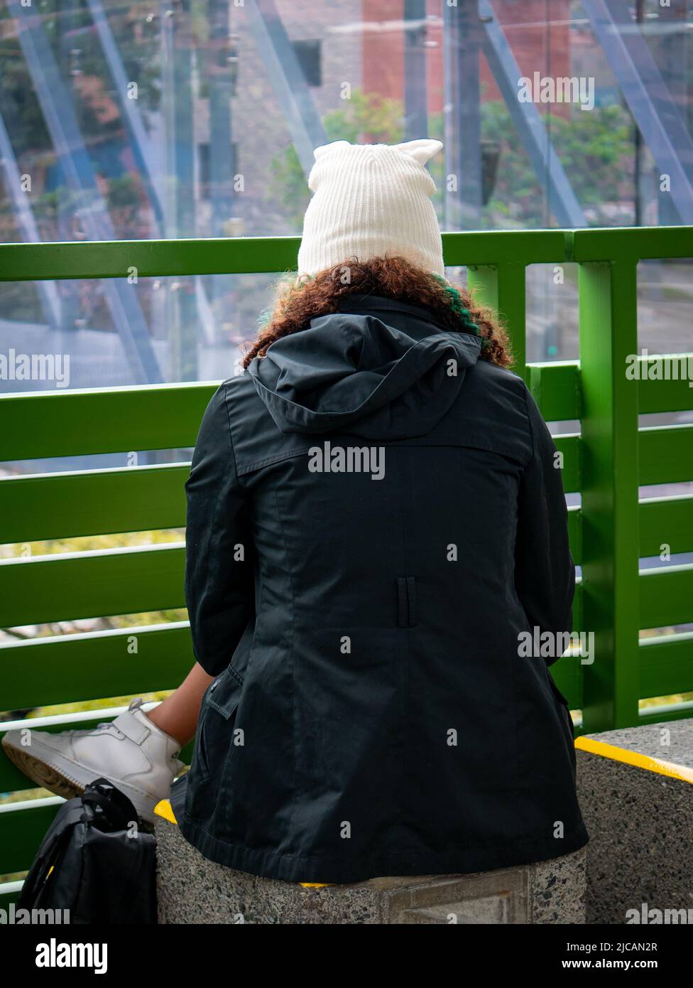 Mujer marrón con zapatos de tenis blancos, chaqueta negra y un cálido gorro  blanco está sentado en la estación de metro esperando Fotografía de stock -  Alamy