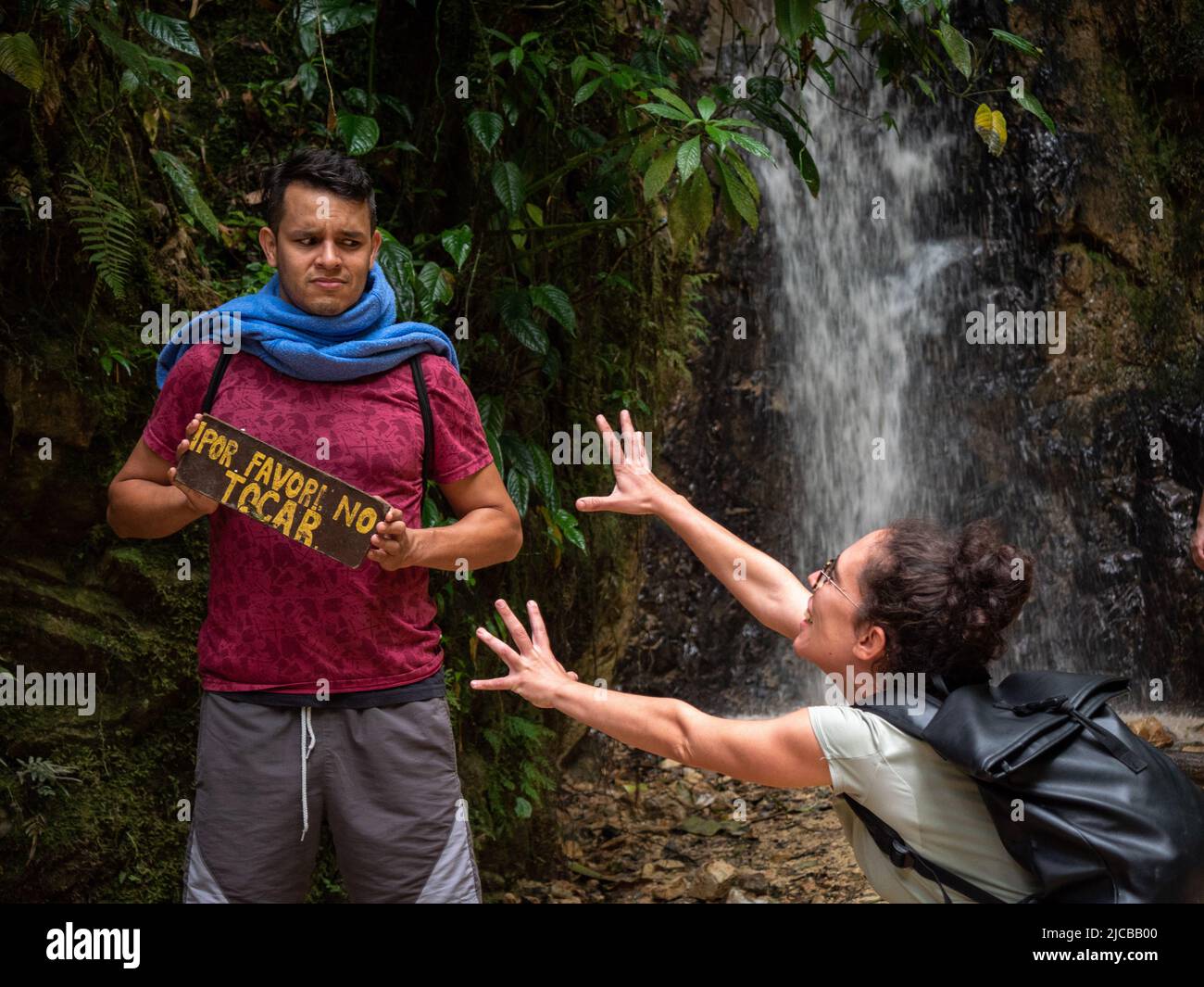 La Estrella, Antioquia, Colombia - Febrero 13 2022: El joven hombre marrón tiene una señal que dice 'Por favor no toque' y la joven mujer curly intenta tocar Foto de stock