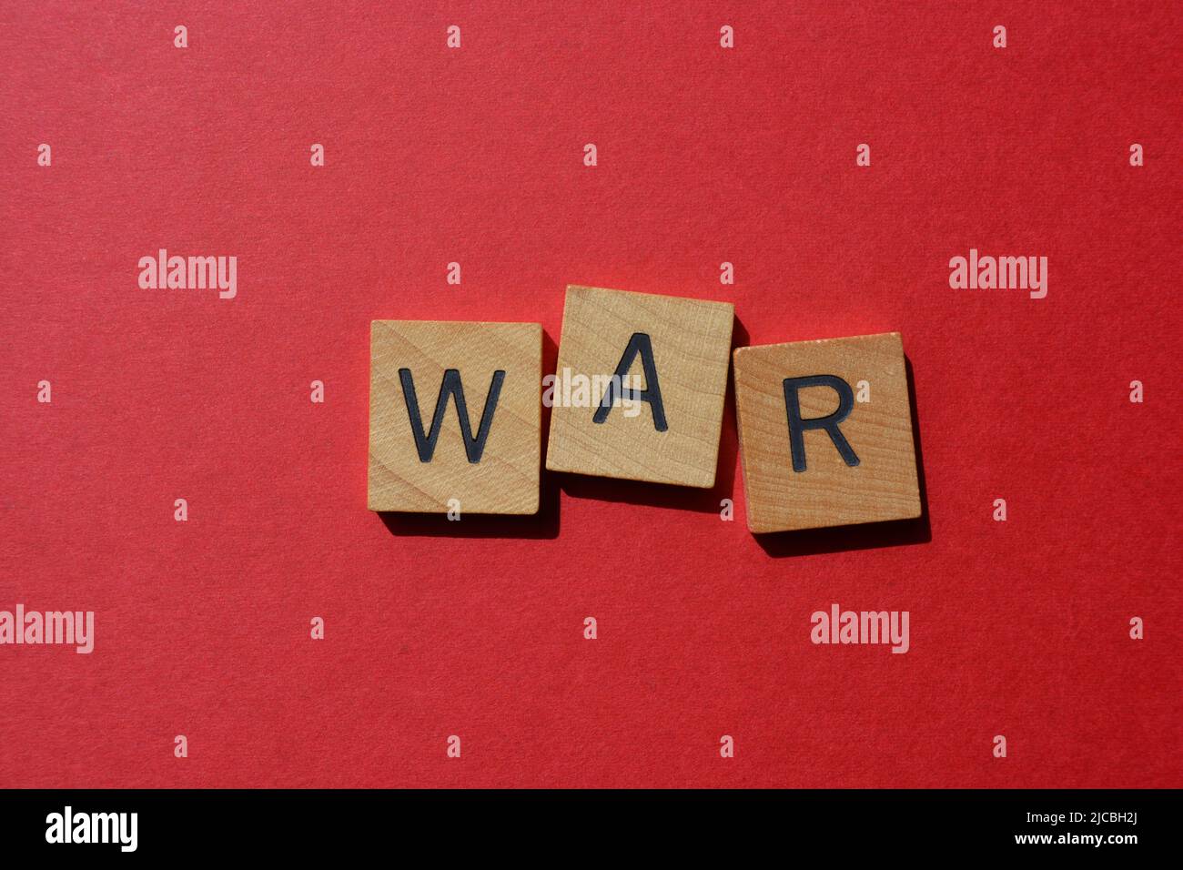 Guerra, palabra en letras del alfabeto de madera aisladas sobre fondo rojo brillante Foto de stock