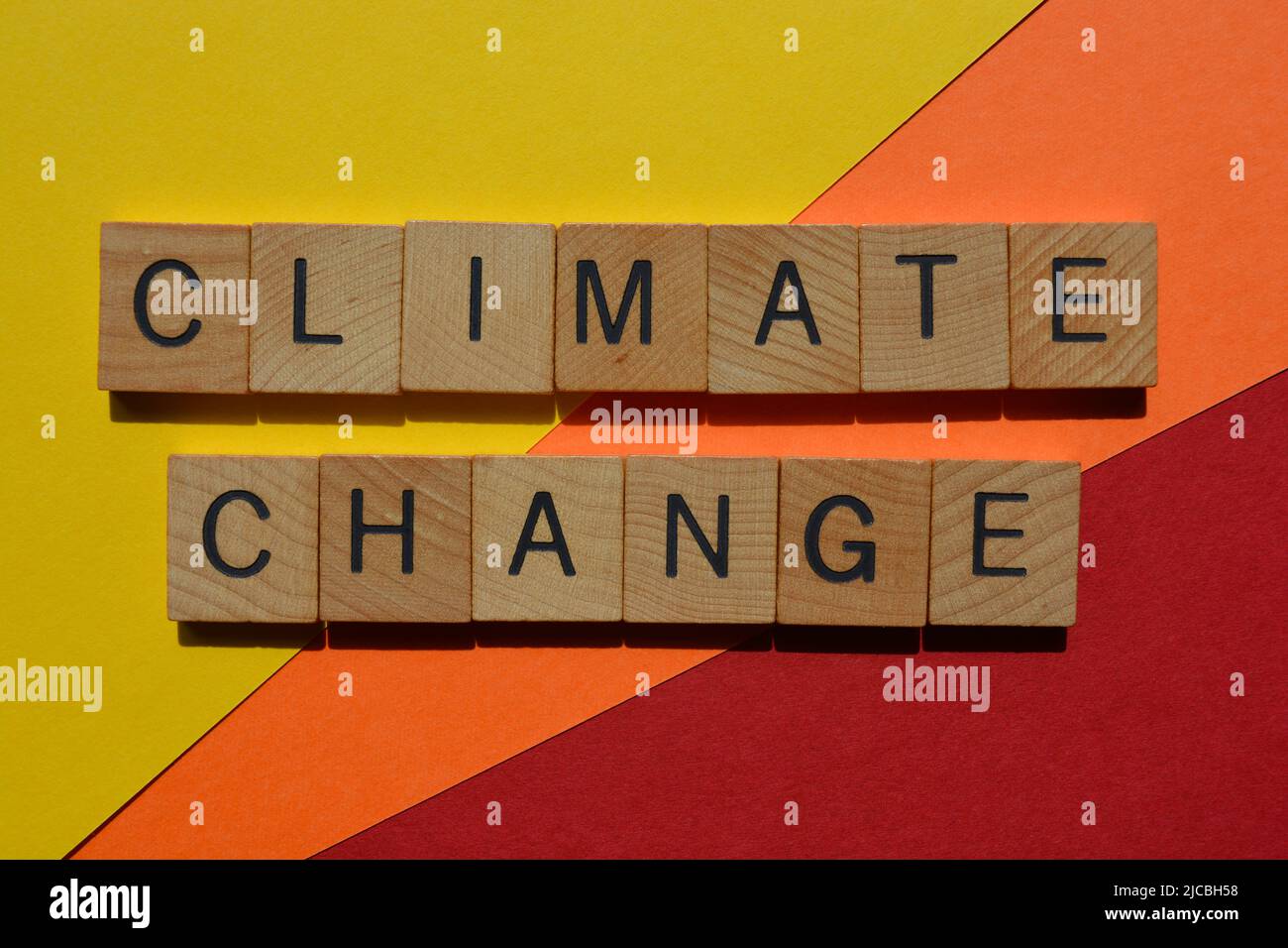 Cambio climático, palabras en letras de alfabeto de madera aisladas sobre fondo rojo, naranja y amarillo Foto de stock