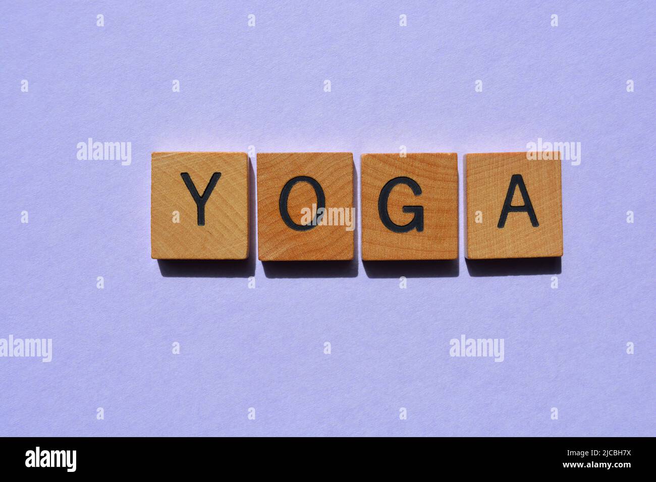 Yoga, palabra en letras del alfabeto de madera aisladas sobre fondo púrpura Foto de stock