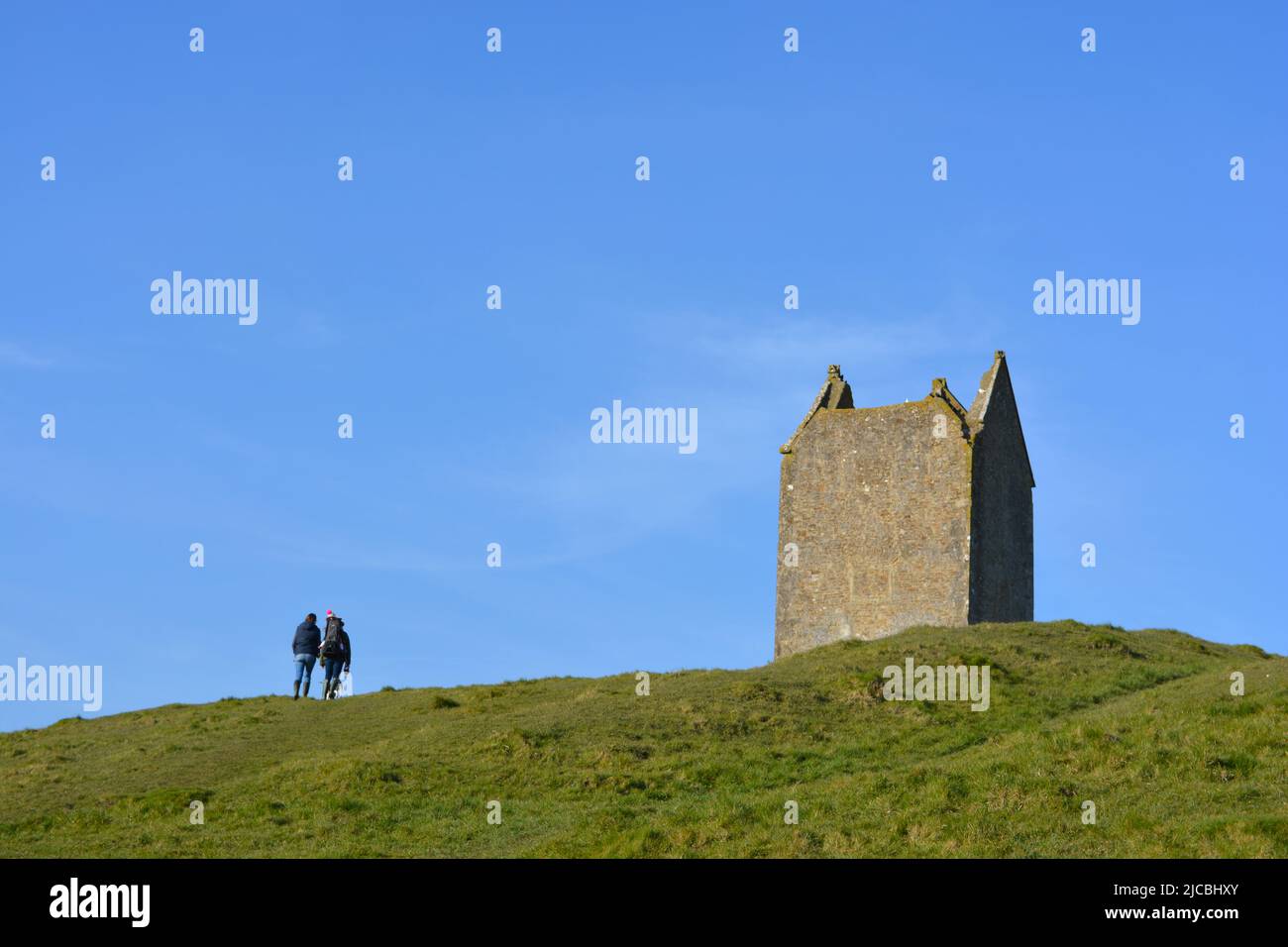 Bruton, Somerset, Inglaterra. Wwalkers en la cima de la colina cerca del Palomar, una histórica torre de piedra caliza construida entre 15th y 17th siglos, ahora un grado II li Foto de stock