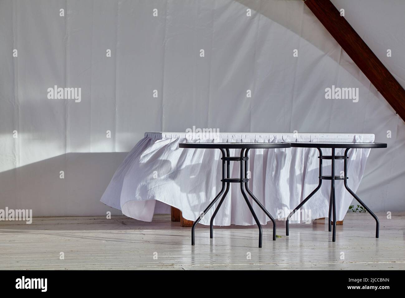 Un mantel blanco sobre la mesa revolotea en la brisa en un pabellón de bodas vacío. Fin de la ceremonia Foto de stock