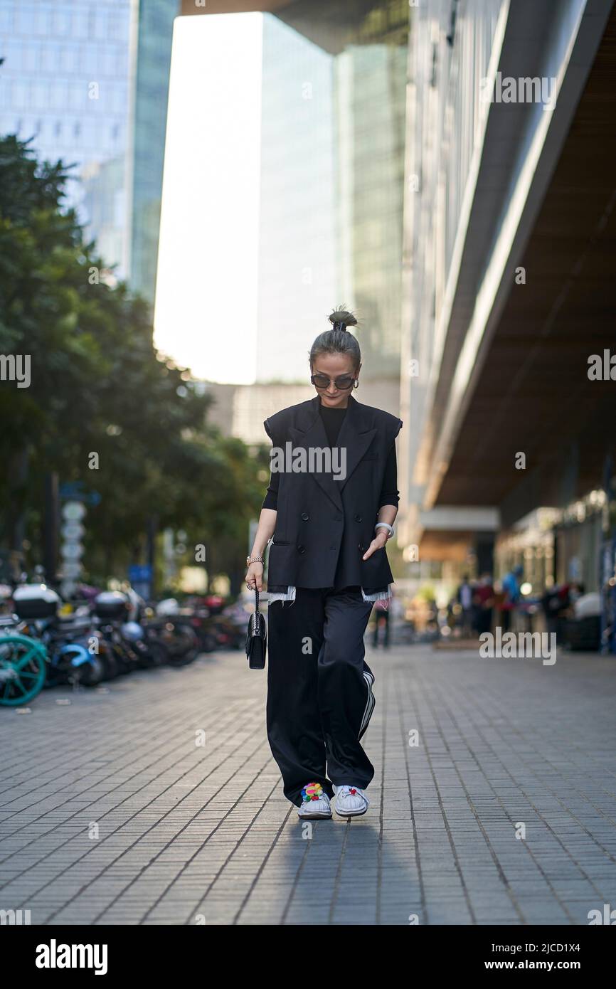 mujer asiática de mediana edad de moda caminando por la calle Foto de stock