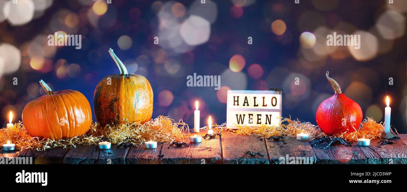 Halloween de fondo. Calabazas y velas encendidas sobre una mesa de madera Foto de stock