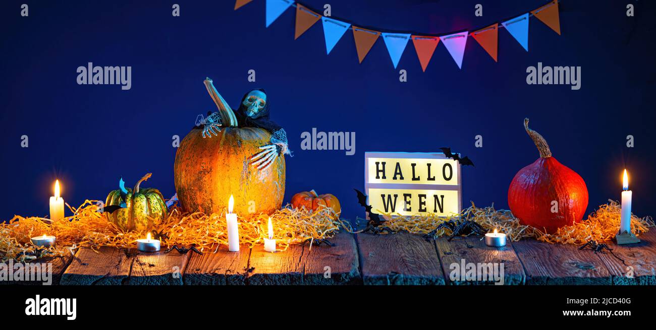 Halloween de fondo. Calabazas y velas encendidas sobre una mesa de madera Foto de stock