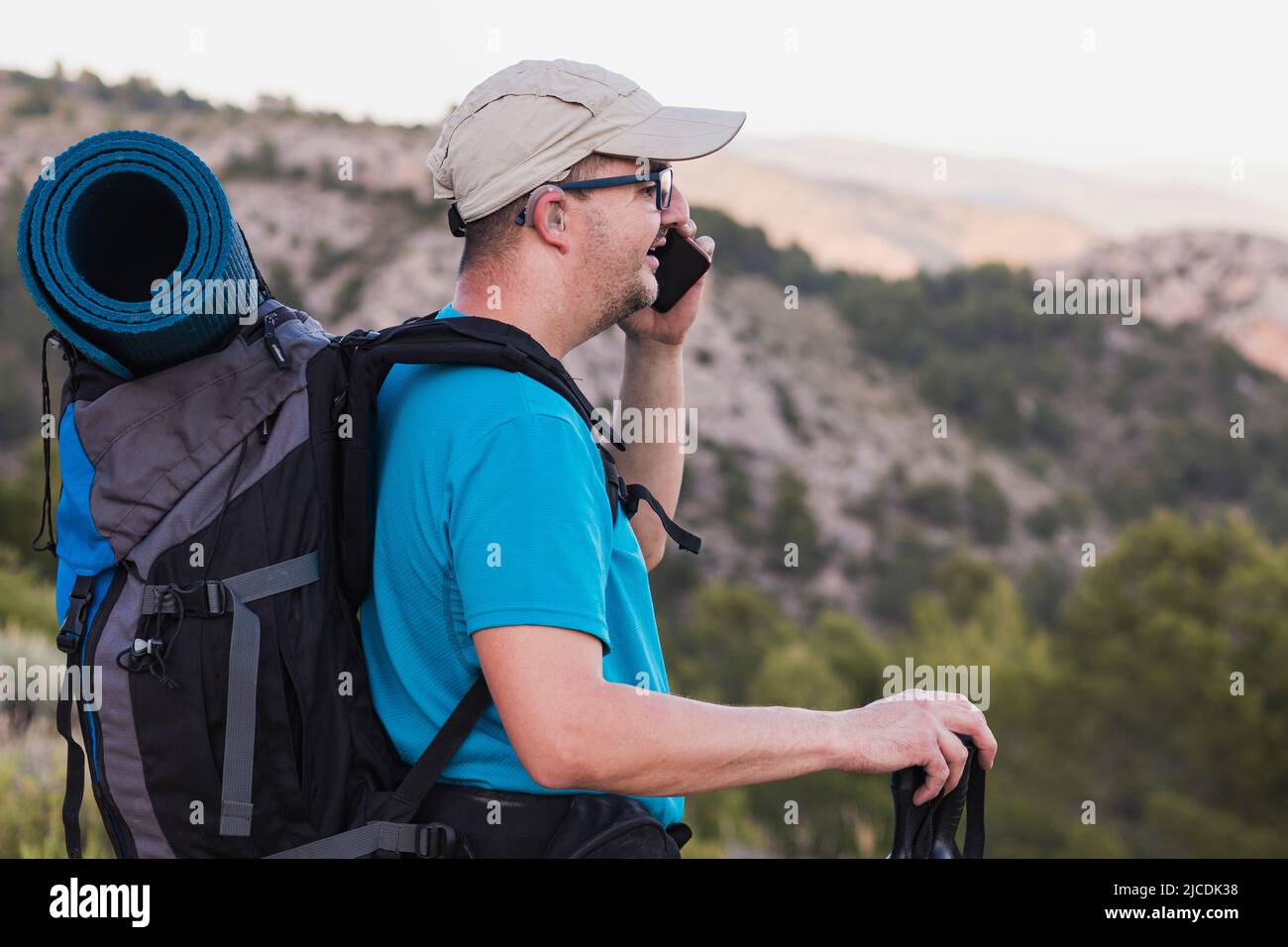 Un excursionista, adulto, hombre, caucásico, con una mochila, Estera,  polos, vestida con una camiseta azul, gorra y pantalones grises con  audífonos y gafas Fotografía de stock - Alamy
