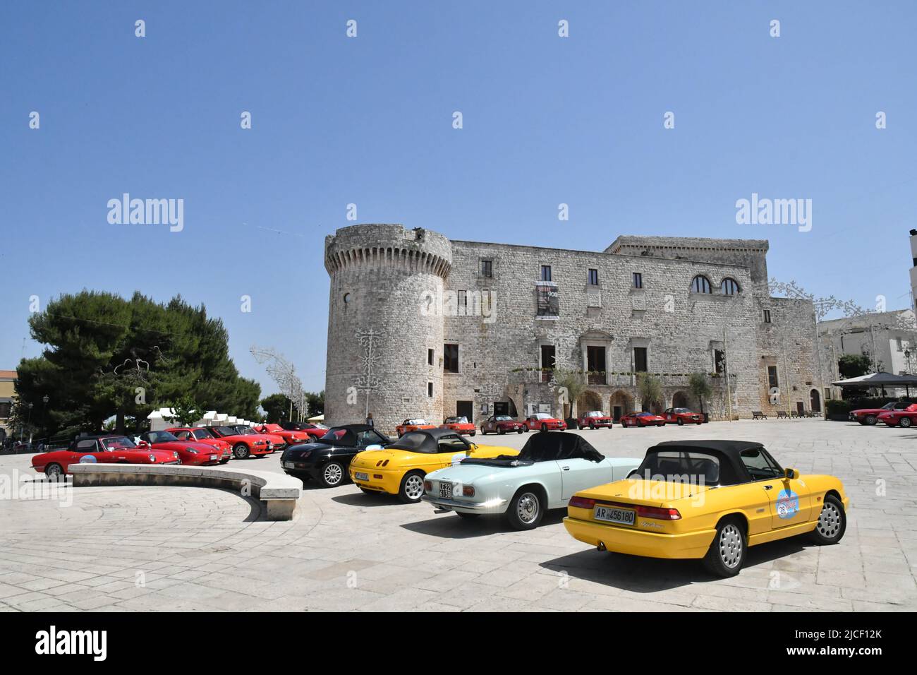 Recogida de coches deportivos frente al castillo de Conversano, una ciudad antigua del sur de Italia. Foto de stock