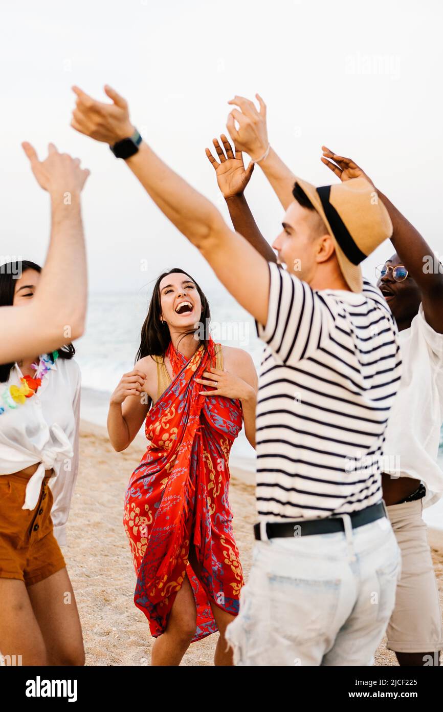 Felices jóvenes amigos bailando en la fiesta de verano en la playa Foto de stock