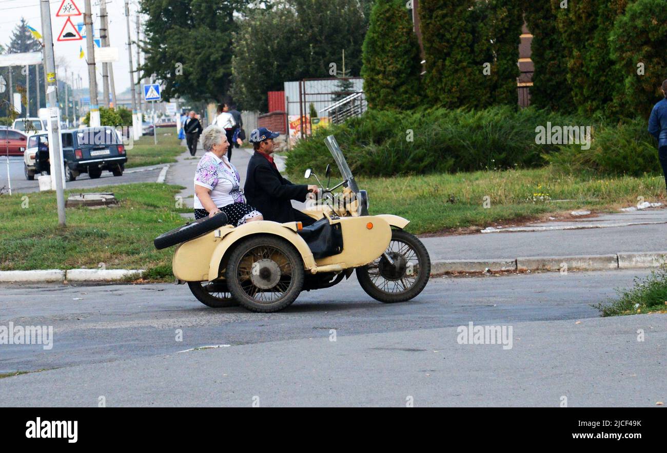 Una pareja ucraniana montando una motocicleta soviética de época con un sidecar en Zashkiv, Ucrania. Foto de stock