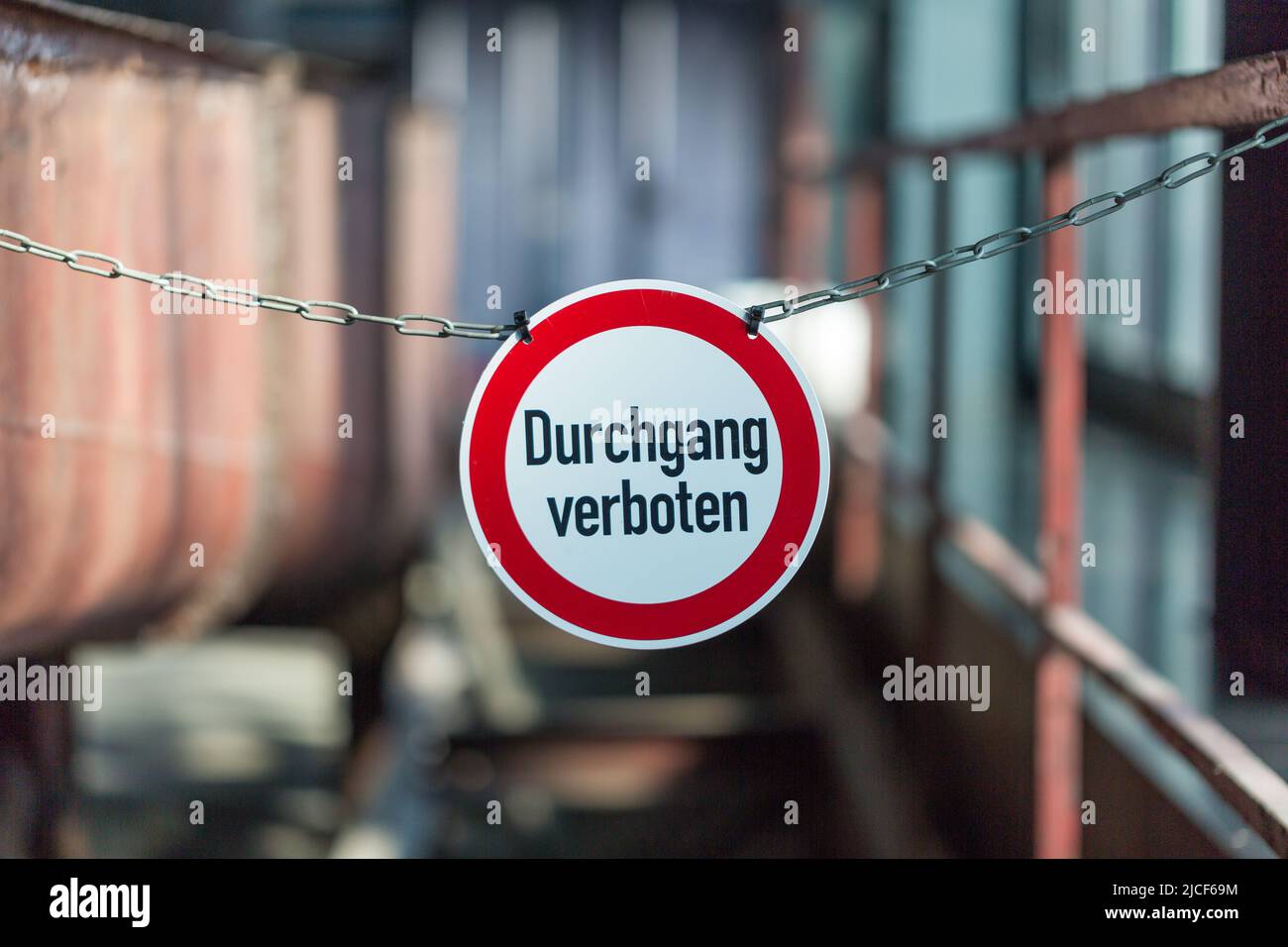 Essen, Alemania - Mar 26, 2022: Durchgang verboten (paso o acceso denegado) signo dentro de una fábrica. Signo redondo, colgado en una cadena. Fondo borroso. Foto de stock