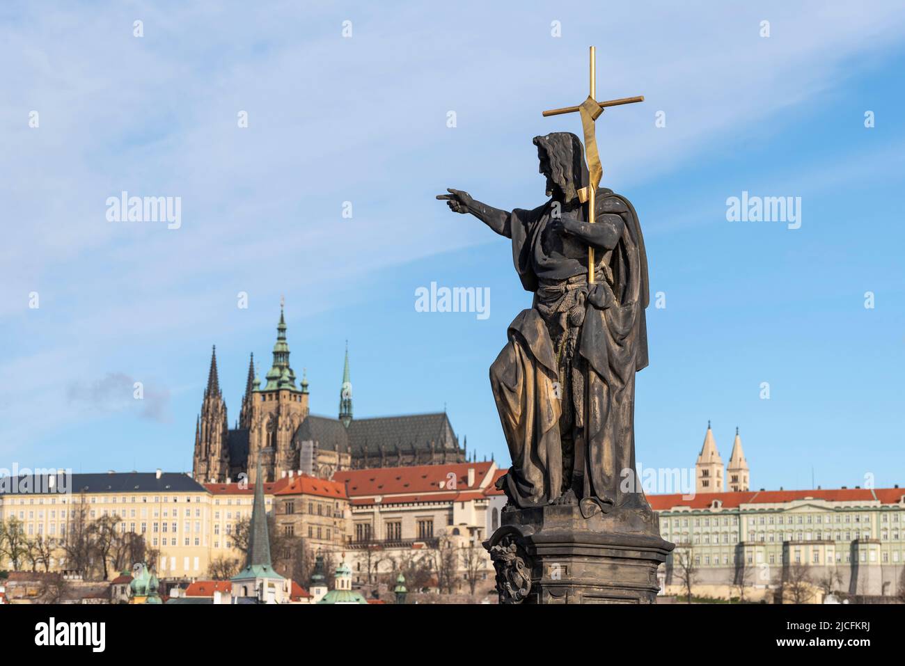 San Juan Bautista, escultura de san Juan en el Puente de Carlos, Castillo de Praga con la Catedral de San Vito detrás, Praga, República Checa Foto de stock