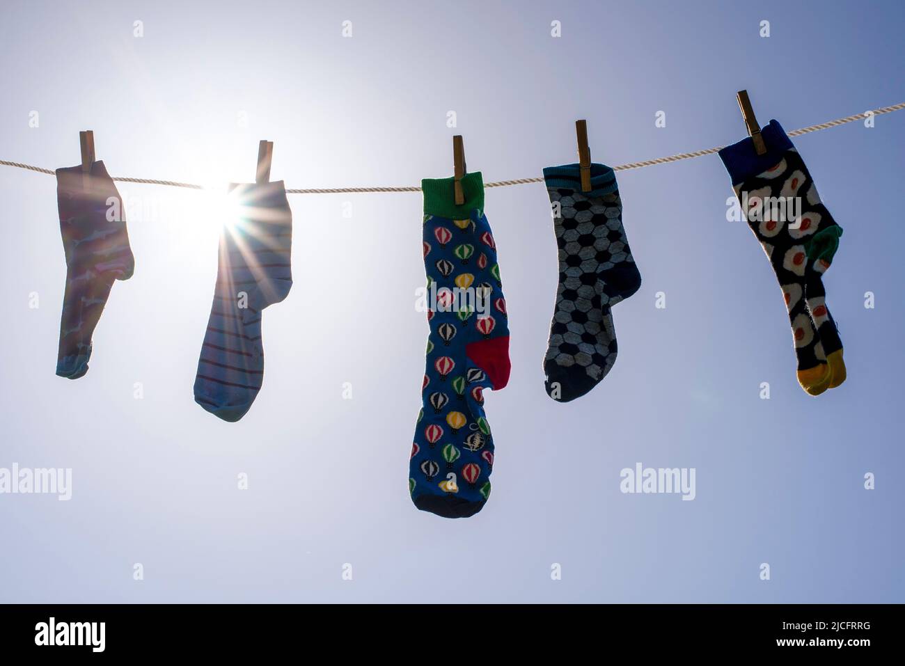 Solitarios calcetines diferentes sin pareja en una línea de ropa, símbolo de imagen 'Lost Calcetines Memorial Day'. Foto de stock