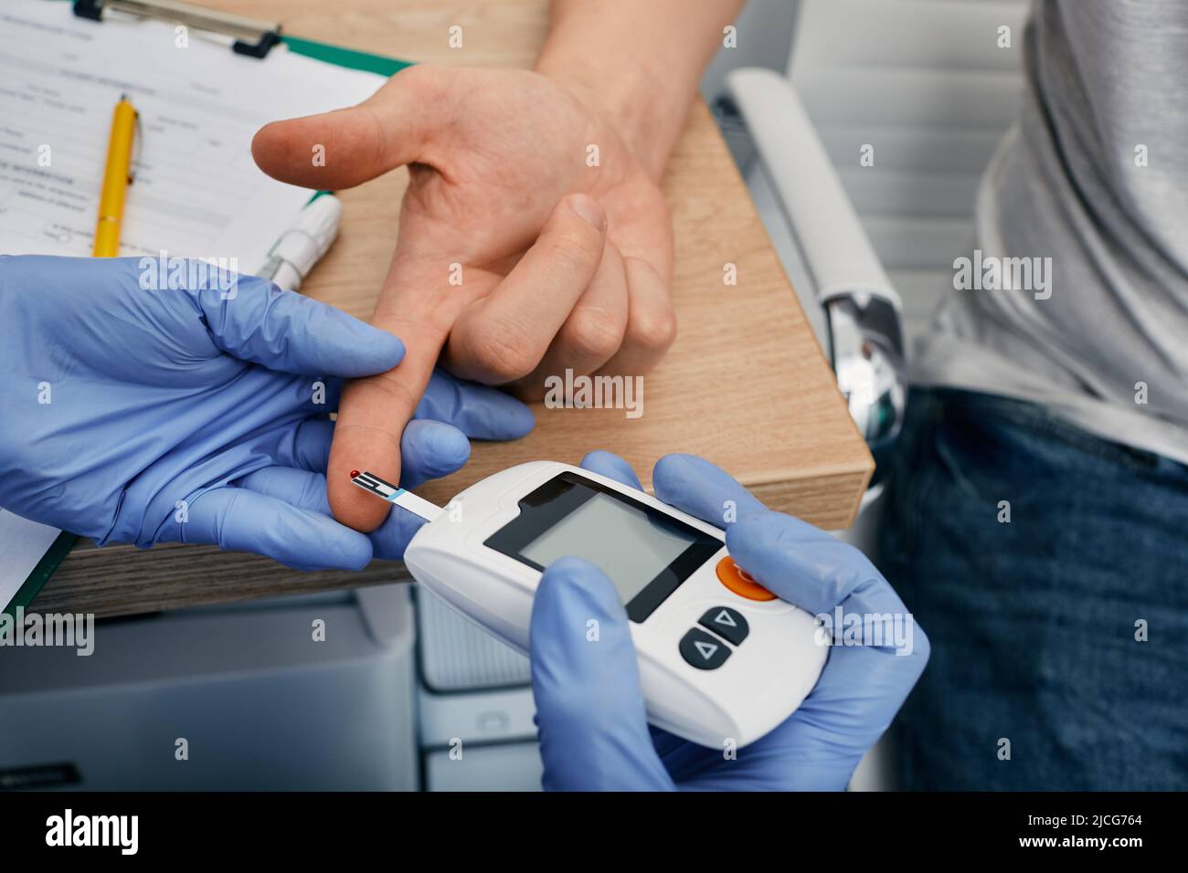 Médico que revisa el nivel de glucosa en sangre de un paciente diabético usando glucómetro, primer plano. Endocrinología, control del azúcar en la sangre Foto de stock