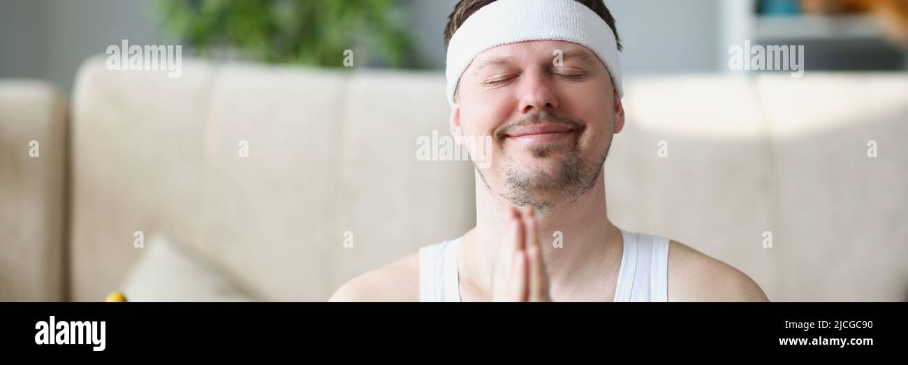 El hombre de mediana edad meditando en casa puso las manos en el gesto namaste Foto de stock