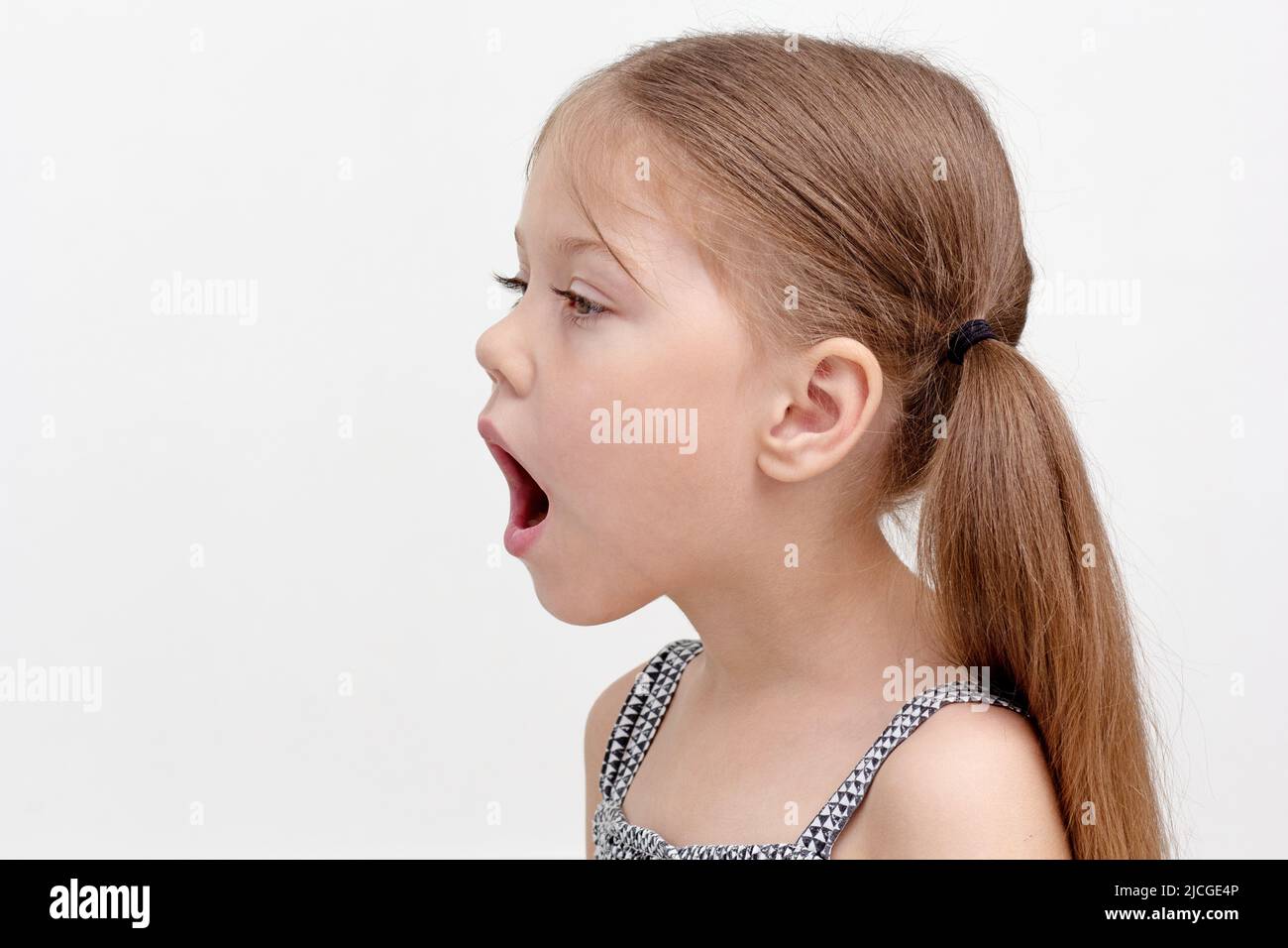 Niña caucásica de 6 años con boca abierta para mostrar dificultad en el habla, pronunciación de sonido y voz combinada con alteración articular Foto de stock